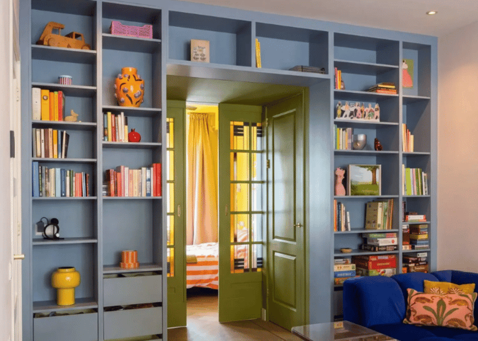 Mur bibliothèque sur mesure en Silver Blue jusqu’au plafond autour d’un passage, avec cases ouvertes et tiroirs en bas