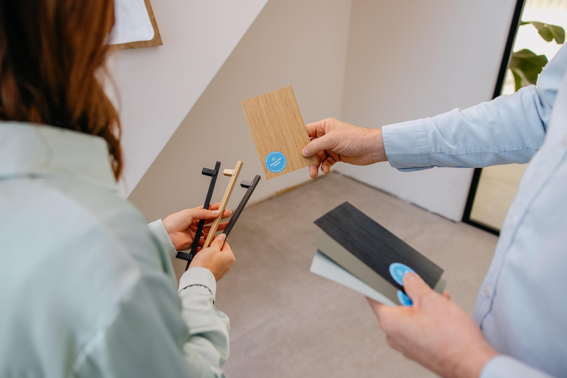 Un homme et une femme examinent des poignées et des échantillons de couleurs pour des armoires sur mesure.