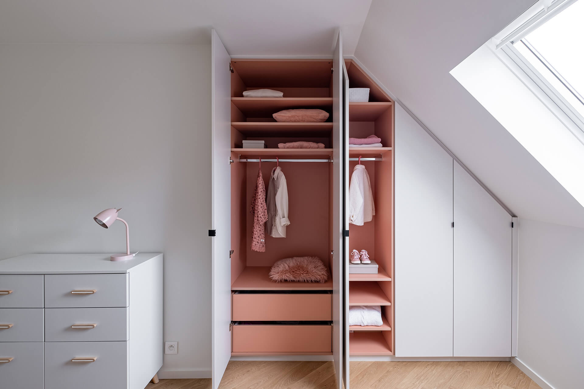 Armoire sur mesure avec un côté en pente et un intérieur rose.