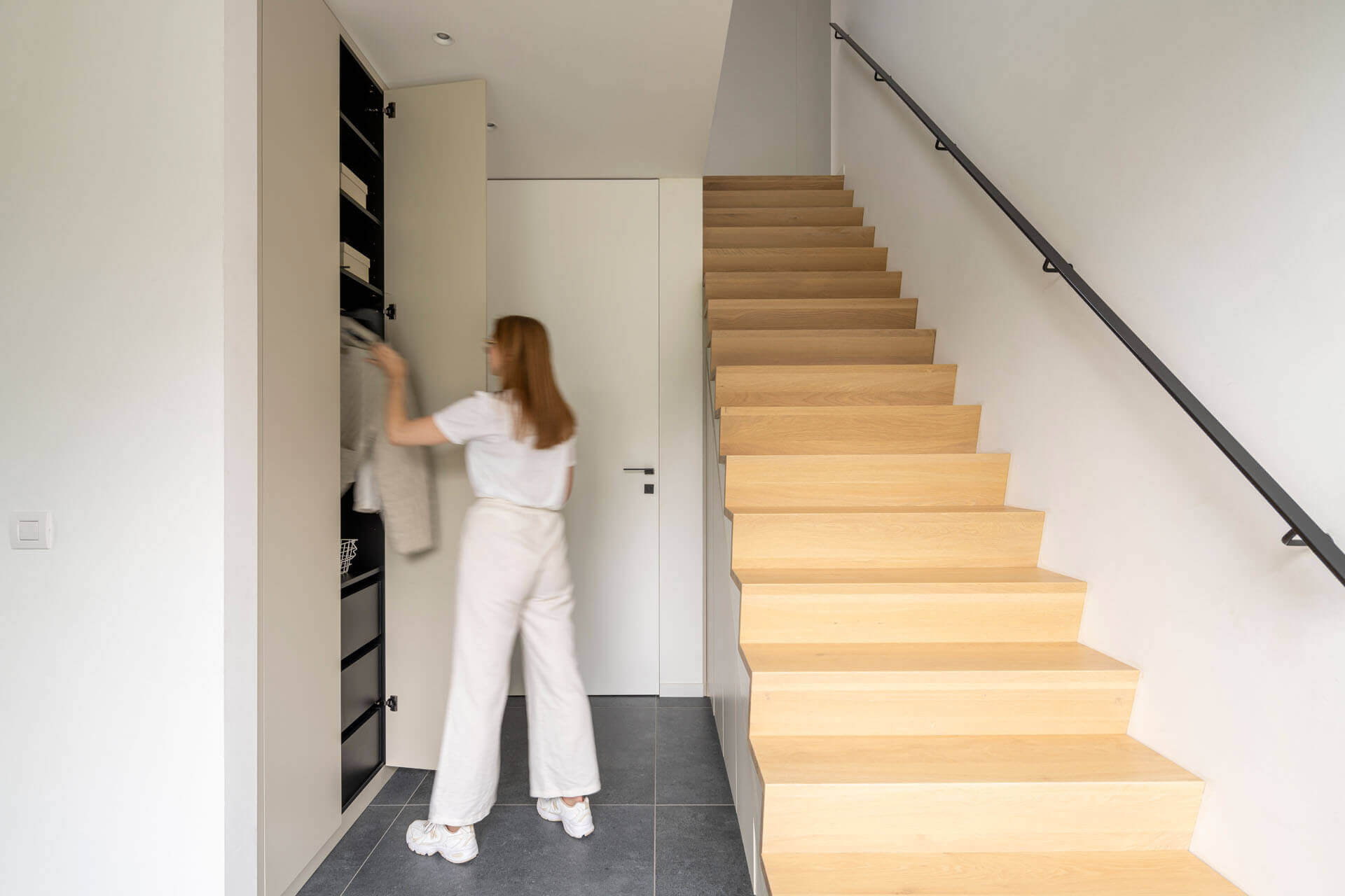 Femme dans le hall avec une armoire sous escalier sur mesure, prenant quelque chose dans le vestiaire sur mesure