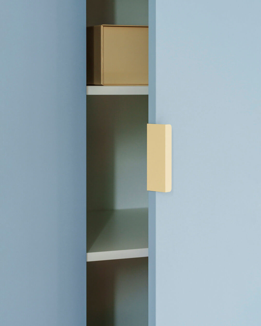 Détail d'une poignée de tonton de couleur crème sur une armoire de couleur bleu argenté