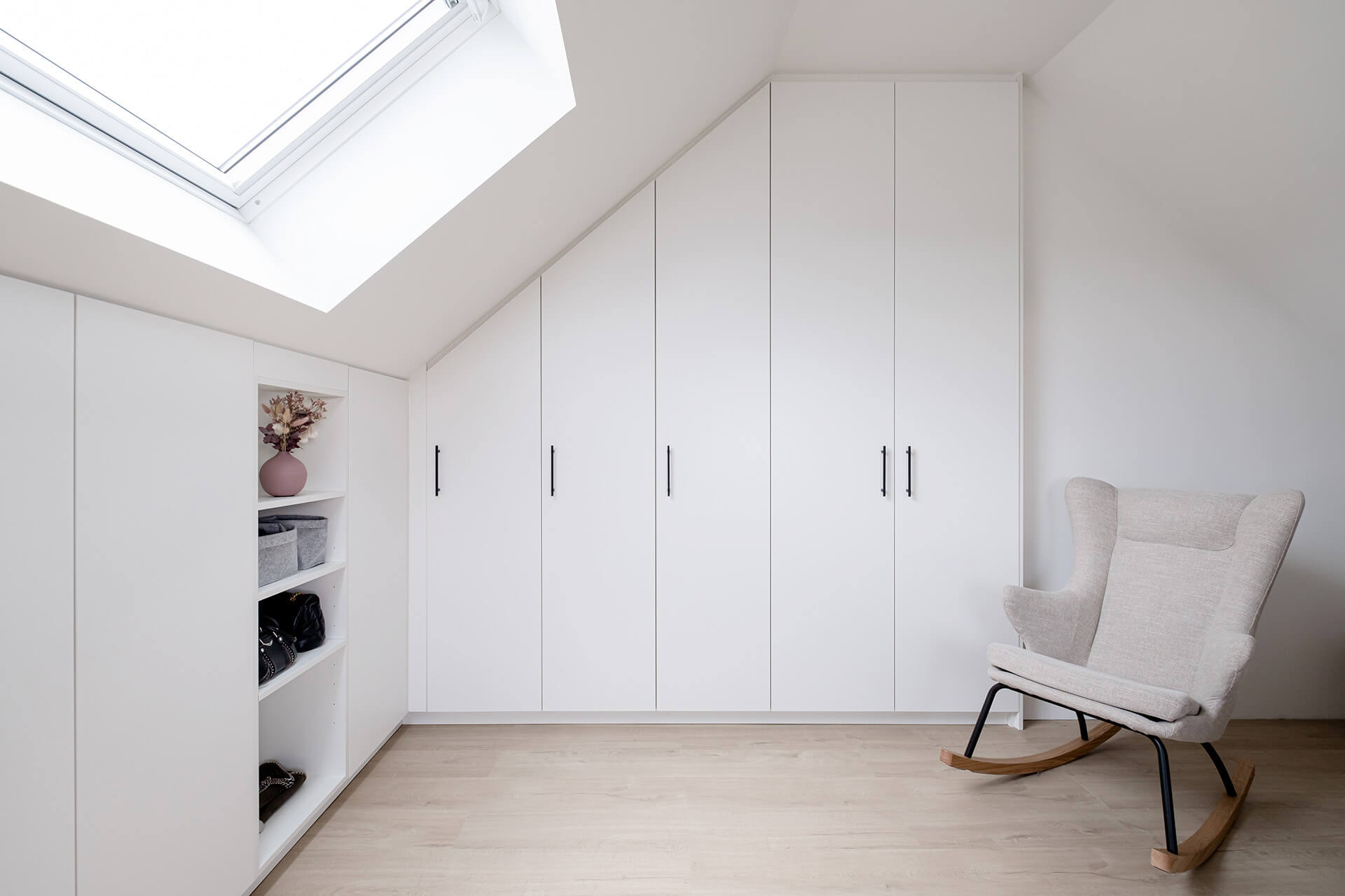 Armoires de rangement blanches sur mesure à placer sous un toit mansardé