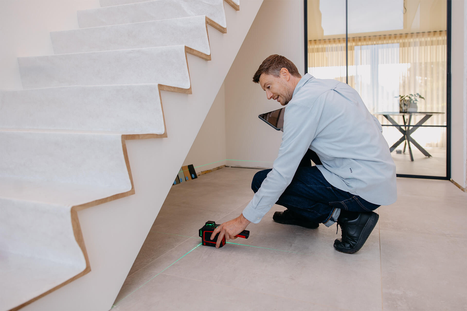 L'expert en mesures évalue l'espace où un meuble sur mesure doit être installé, sous un mur incliné.