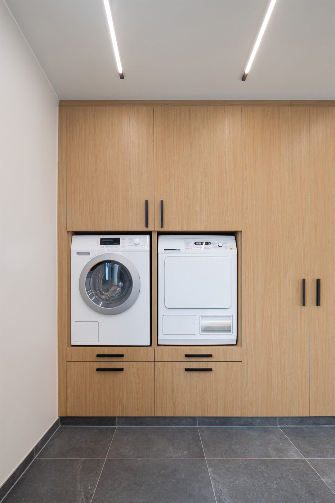 Meuble sous-lave-linge sur mesure en chêne naturel Essential avec poignée barre noire mate, vue de face fermée