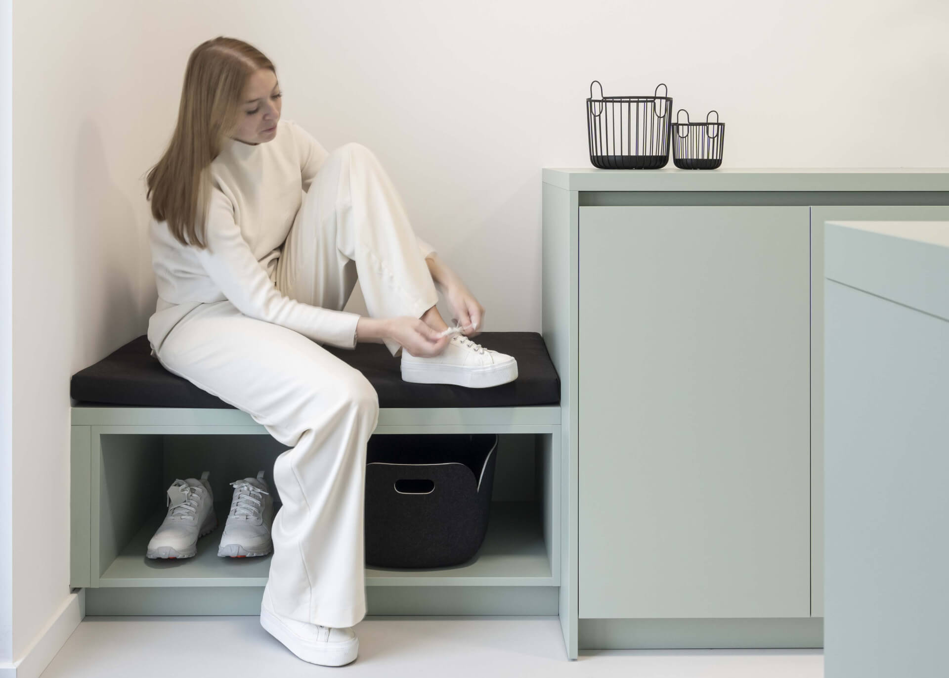 Une femme se chausse sur un canapé sur mesure de couleur Industrial Green.