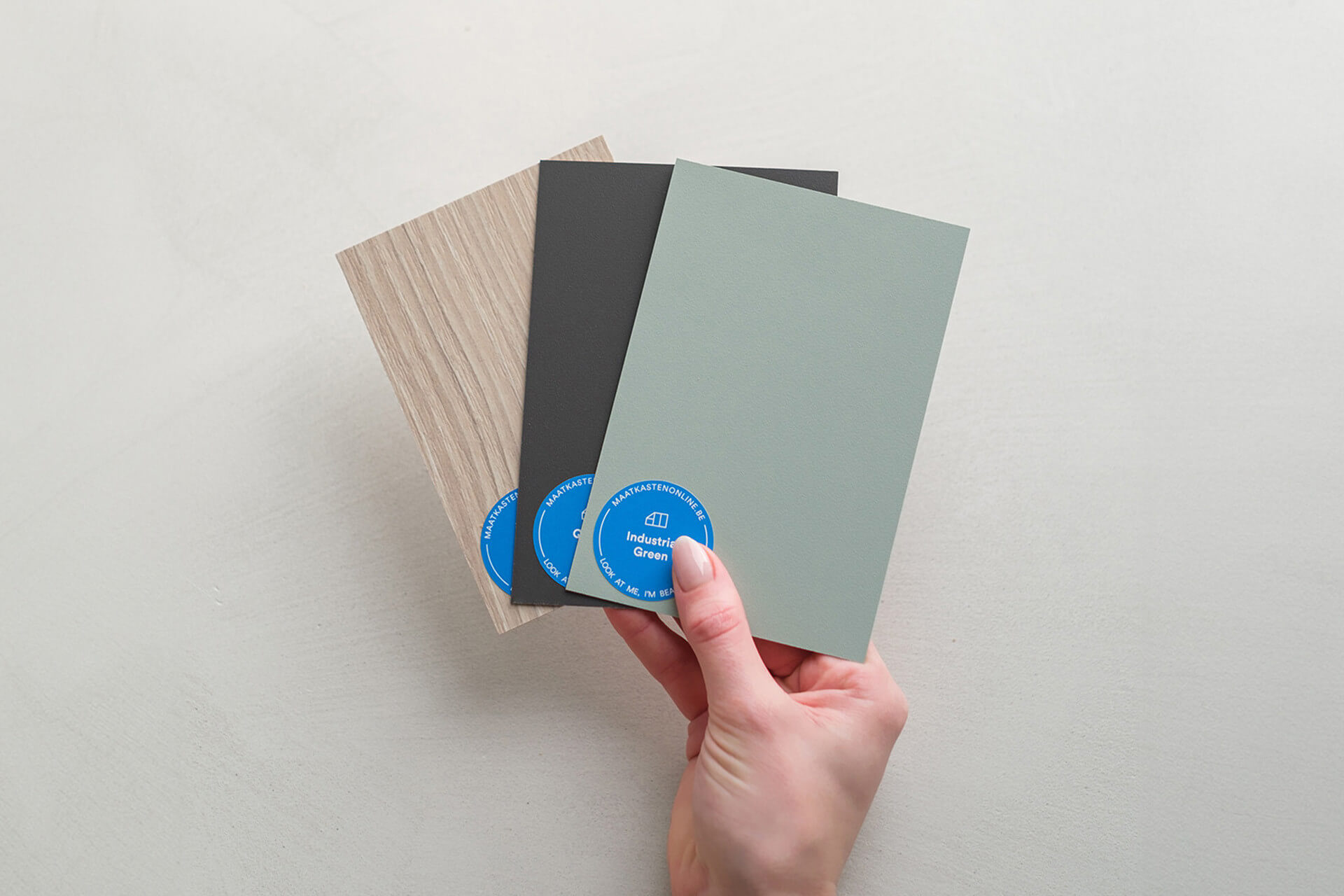 Une main tenant trois échantillons de couleur pour un meuble sur mesure, provenant de Custoro