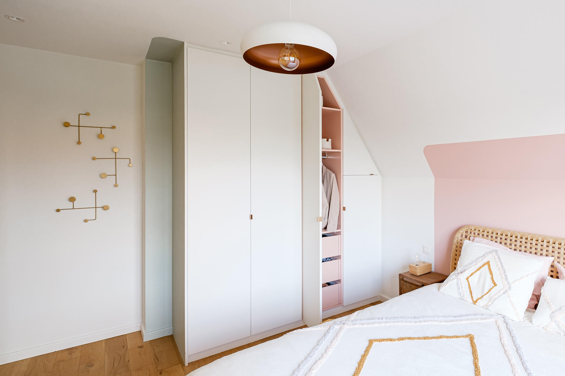 Armoire sur mesure en blanc et rose sous un toit en pente dans une chambre d'enfant