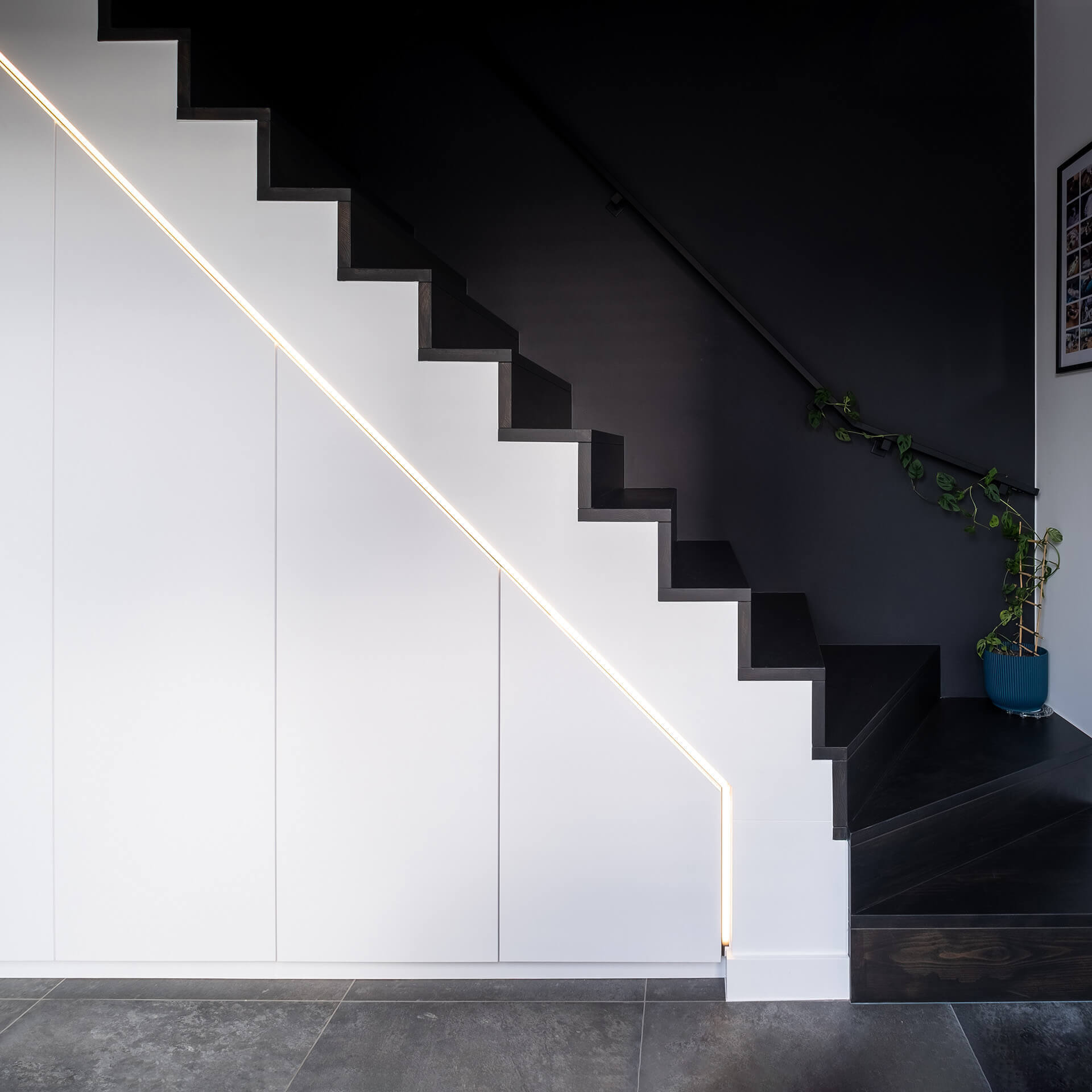 Hall avec un escalier noir et une armoire sous escalier sur mesure blanche