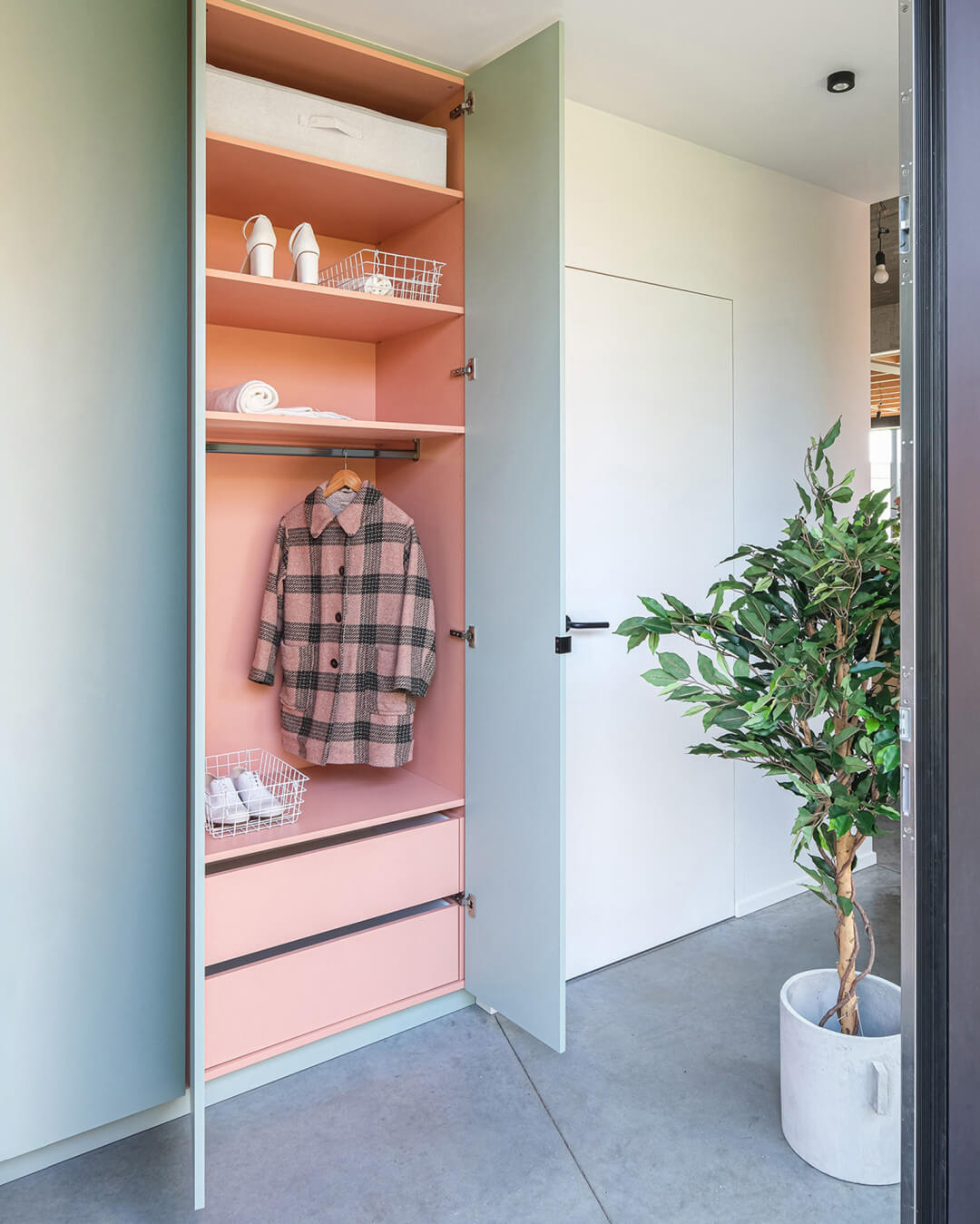 Armoire sur mesure pour le vestiaire en couleur 'Industrial Green' avec intérieur rose, dans une maison moderne