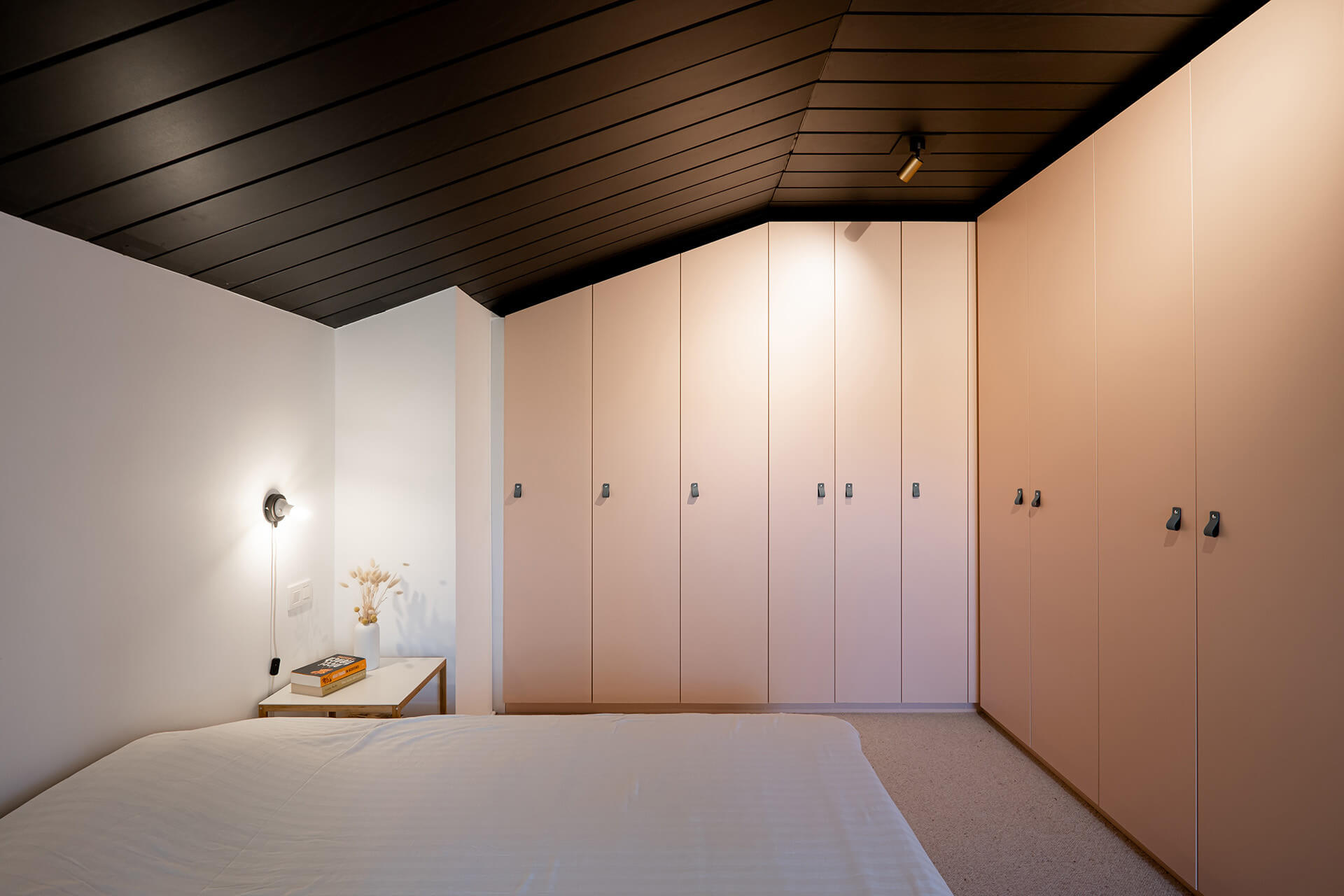 Armoire d'angle rose sur mesure sous un toit en pente dans la chambre à coucher