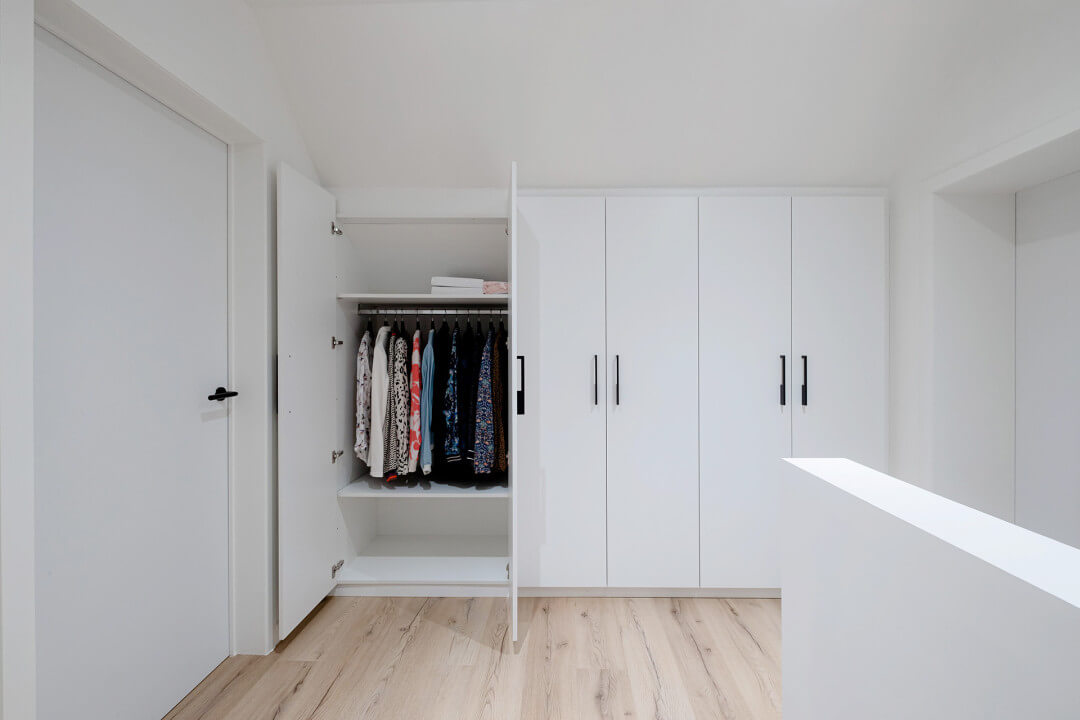 Garde-robe blanche sur mesure avec un arrière en pente qui suit la ligne du toit