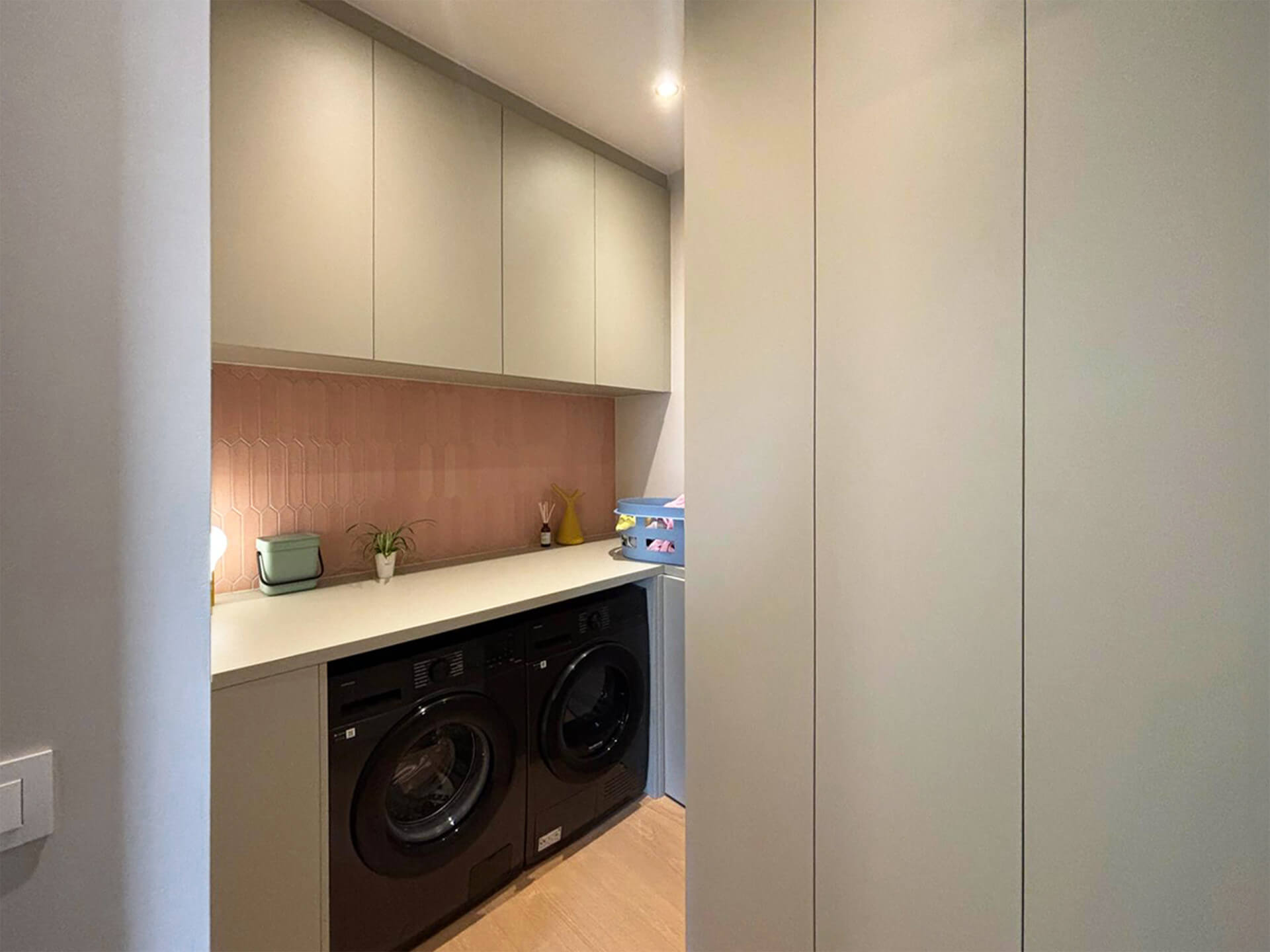 Meuble sous-lave-linge sur mesure, couleur vert Natural Sage, avec placards de rangement sur mesure également couleur sauge naturelle.