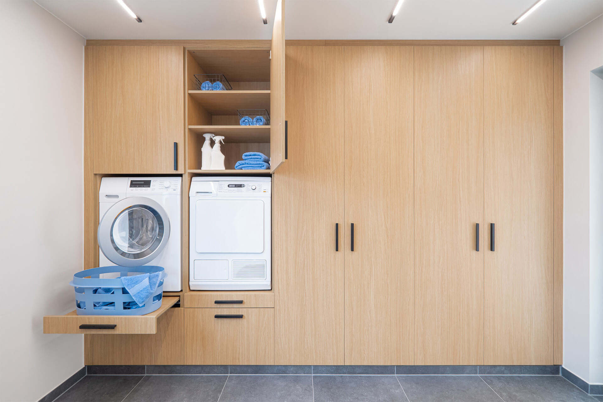 Une armoire haute avec lave-linge et sèche-linge dans un débarras