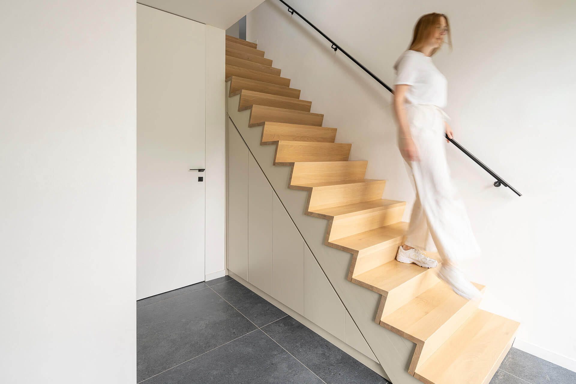 Femme descendant les escaliers dans un hall avec une armoire sous escalier sur mesure