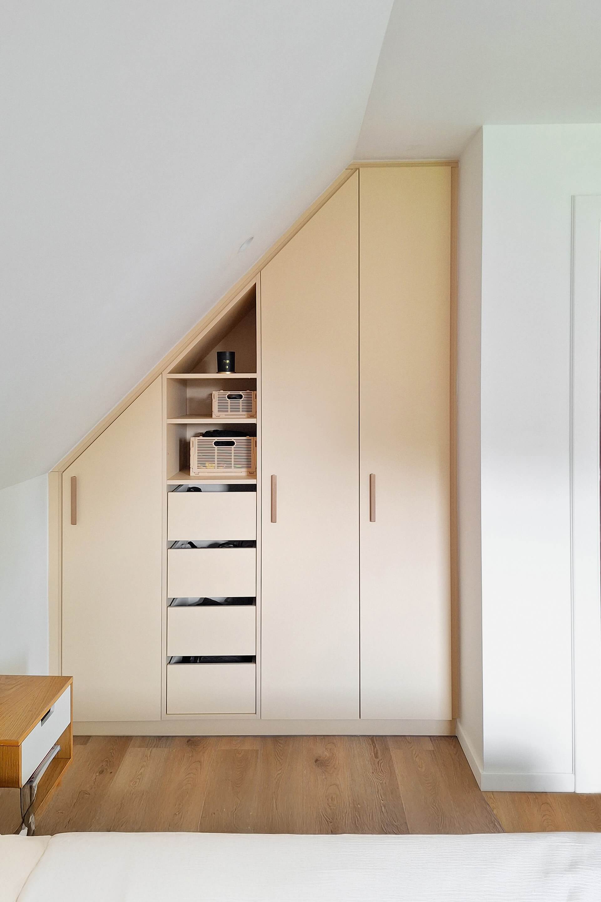 Armoire blanche sur mesure, de forme inclinée, avec poignées Bar en laiton.