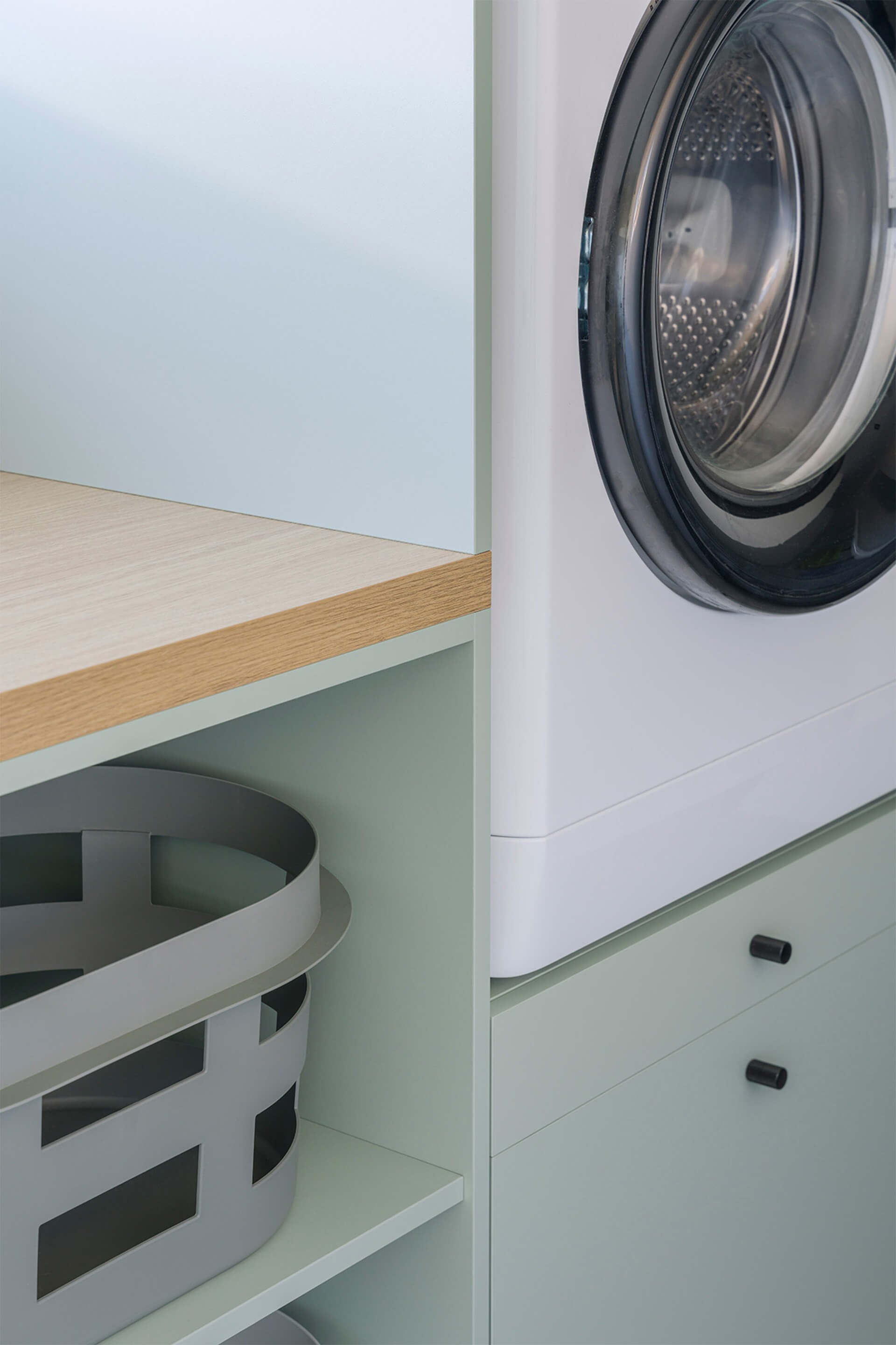 Gros plan sur un meuble de buanderie sur mesure, de couleur Industrial Green avec des poignées Monument noires.