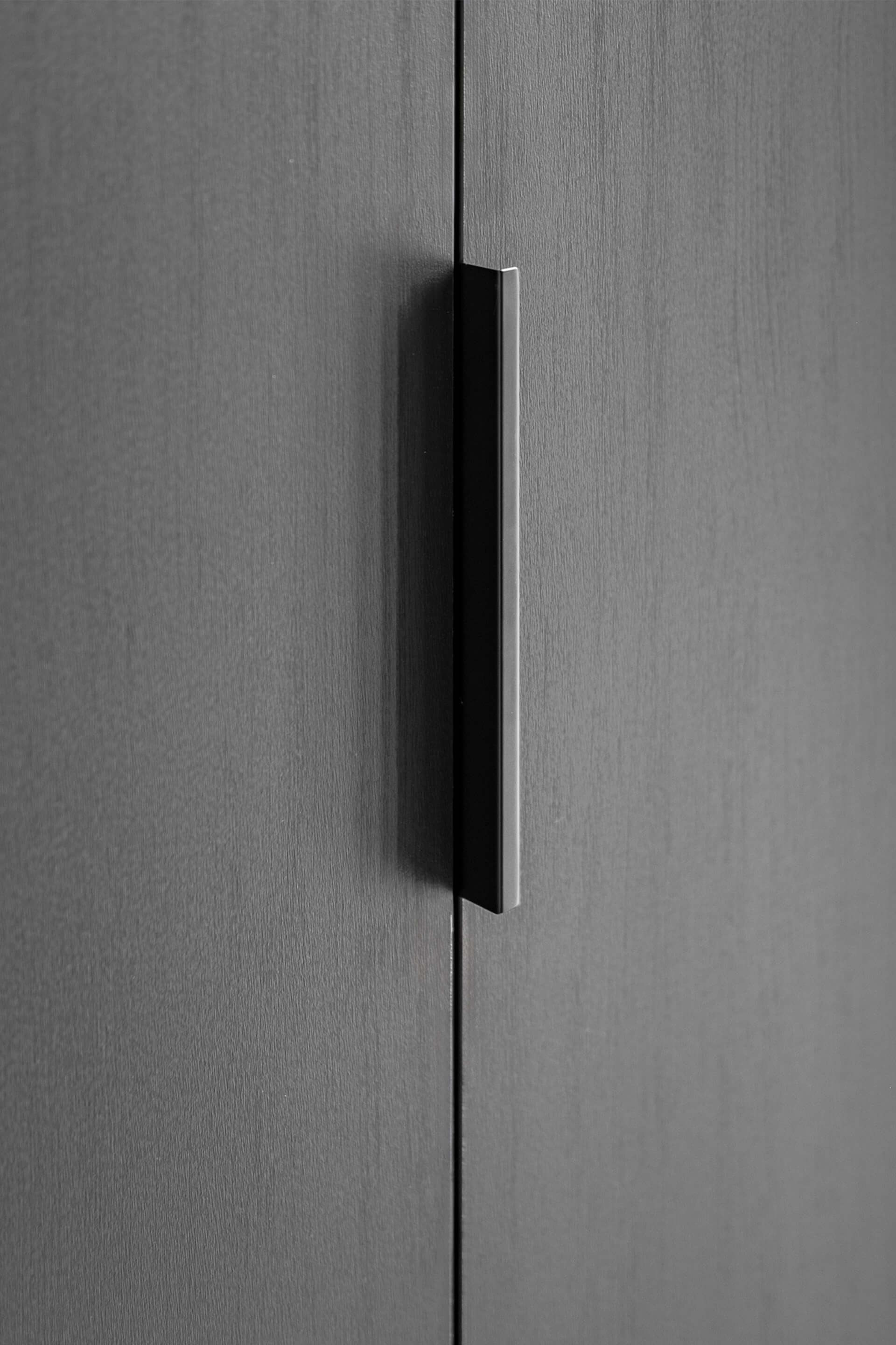 Poignée Pure noire sur un meuble sur mesure en Noir Élégant. Gros plan de la poignée sur un dressing sur mesure.