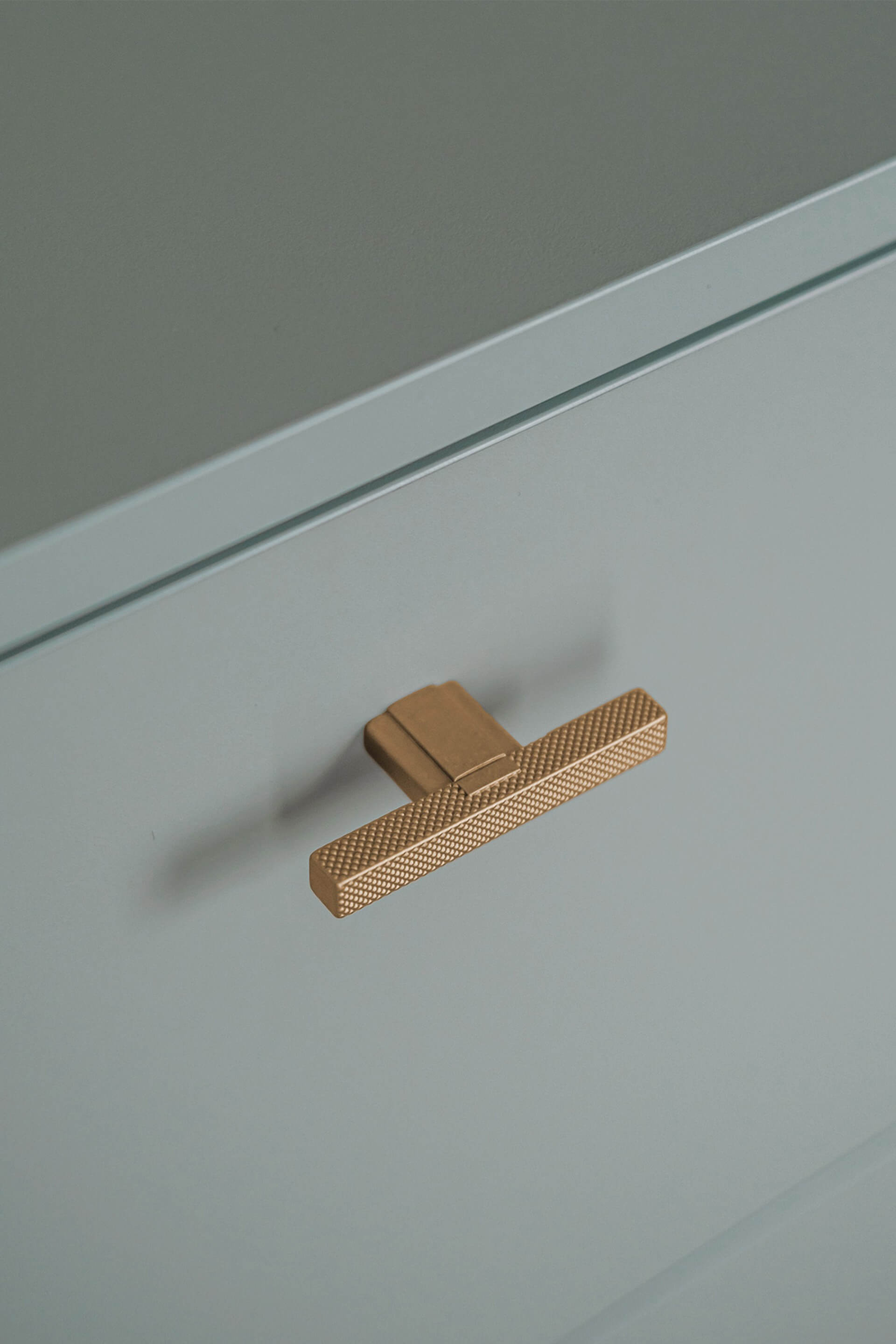 Gros plan sur les poignées en laiton en forme de T-Diamond d'une armoire de rangement sur mesure de couleurr Industrial Green.