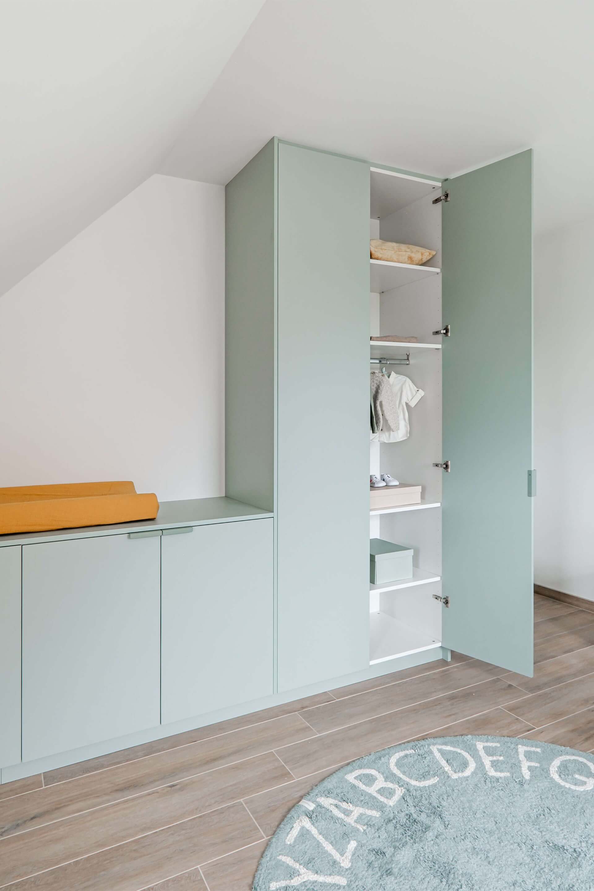 Armoire haute et basse sur mesure, de couleur Industrial Green, avec poignées Tonton vertes. Dans la partie haute de l'armoire, à l'extrême droite, la porte la plus à droite est ouverte.